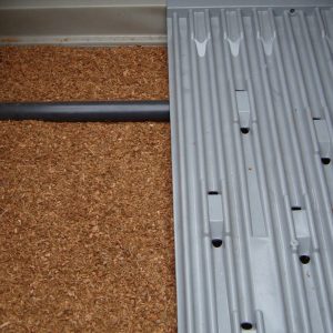 EInblick in eine Kleinkläranlage mit Biofilter. Links ist das Filtermaterial aus Kokosfragementen, rechts die Verteilerwippe für Abwasser zu sehen.