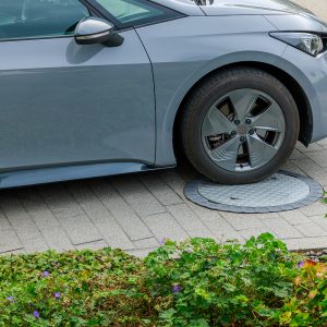 Ein graues Auto rollt über die Schachtabdeckung "PKW-Set" für Erdtanks.